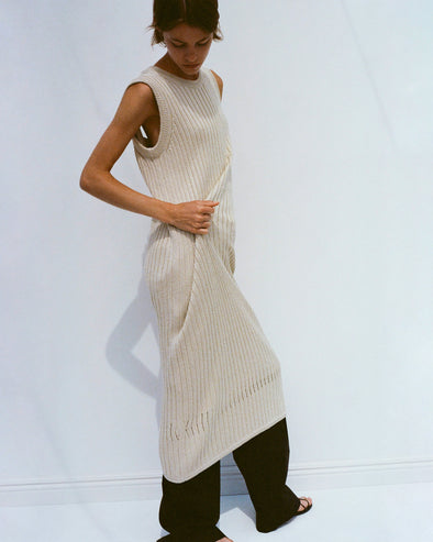 Model wearing Leighton Knit Dress in Dry Rib in light wheat, adjusting fabric with her hands