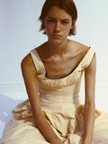 Cropped image of model sitting against white backdrop, wearing Kendall Dress in Tech Cotton in light wheat