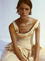 Cropped image of model sitting against white backdrop, wearing Kendall Dress in Tech Cotton in light wheat