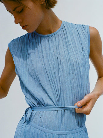 Cropped image of model holding her waistband, wearing Rosalyn Skirt and Lyra Top in Pleated Jersey in pool