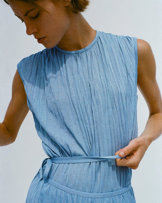 Cropped image of model holding her waistband, wearing Rosalyn Skirt and Lyra Top in Pleated Jersey in pool