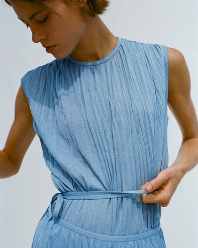 Cropped image of model holding her waistband, wearing Rosalyn Skirt and Lyra Top in Pleated Jersey in pool