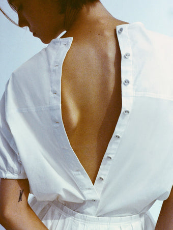Cropped image of model's back wearing Haleigh Top in Cotton Sateen in white with buttons open down her back