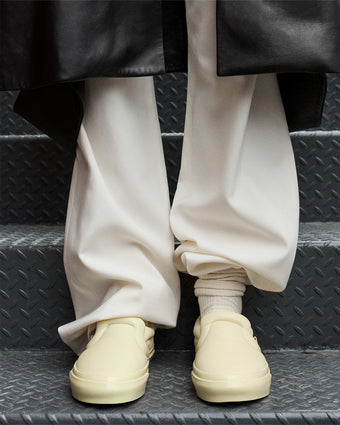 Cropped image of model wearing Vans x Proenza Schouler Puffy Slip-On Shoes in resin, standing on metal staircase