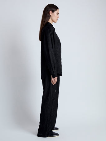 Side full length image of model wearing Hall Shirt in Crinkled Flou in BLACK