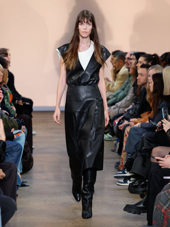 Model in Black Nappa Leather Wrap Dress, Ivory Wool Jersey T-shirt, Black Cone Over The Knee Boots, and Black/gold Horn Pendant Necklace