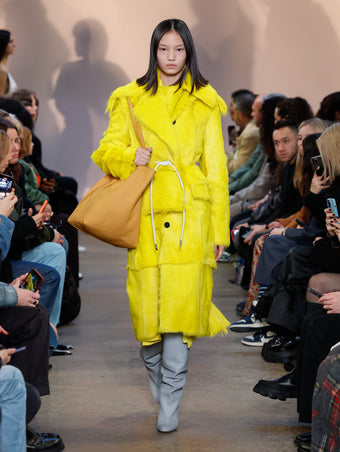 Model in Yellow Toscana Shearling Coat, Yellow Crushed Matte Satin Dress, Stone Cone Over The Knee Boots, Ginger Xl Ps1 Tote, and White Smooth Nappa Strobel Belt