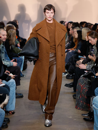 Model in Umber Doubleface Llama Wool Coat, Umber Viscose Wool Sweater, Chestnut Nappa Leather Pant, Silver Bronco Ankle Boots, and Black XL PS1 Tote