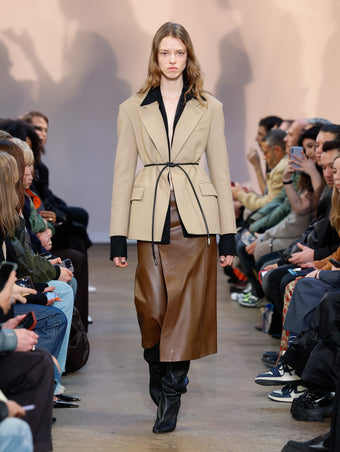 Model in Khaki Wool Felt Jacket, Black Crushed Matte Satin Shirt, Chestnut Nappa Leather Skirt, Black Cone Over The Knee Boots, and Black Smooth Nappa Strobel Belt