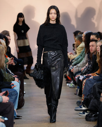 Model in Charcoal Viscose Wool Sweater, Black Nappa Leather Skirt, Black Cone Over The Knee Boots, Black Beacon Saddle Bag, and Black Leather Gloves