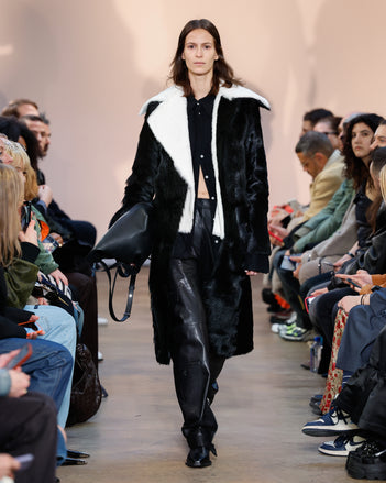 Model in Black Toscana Shearling Coat, Black Crushed Matte Satin Shirt, Black Nappa Leather Motorcycle Pant, Black Bronco Ankle Boots, and Black L PS1 Tote