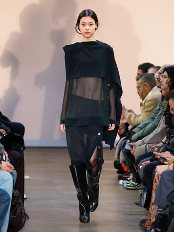 Model in Black Technical Chiffon Top, Black Technical Chiffon Skirt, and Black Cone Boots