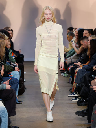 Model in Resin Viscose Gauze Knit Top, Resin Technical Chiffon Skirt, Cream Bronco Ankle Boots, and Gold/silver Ring Necklace