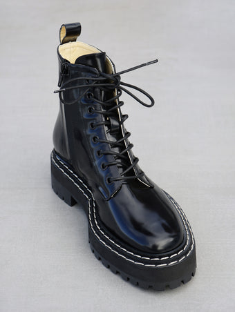Proenza Schouler 3/4 front editorial image of Lug Sole Lace-up Boots in BLACK