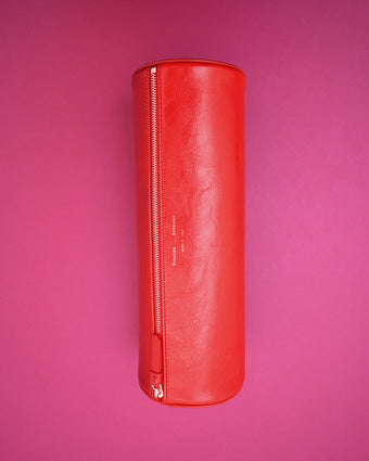 Image of the Silo Clutch in Red Shiny Calf against a pink backdrop